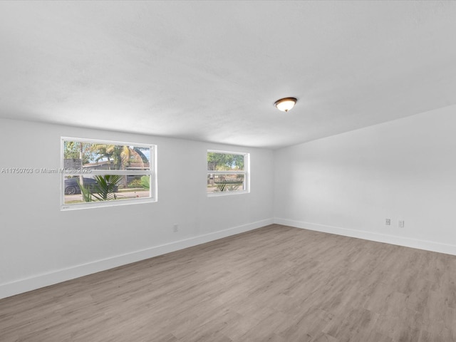 spare room featuring baseboards and wood finished floors