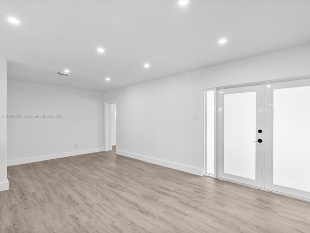 empty room with light wood-style floors, baseboards, french doors, and recessed lighting