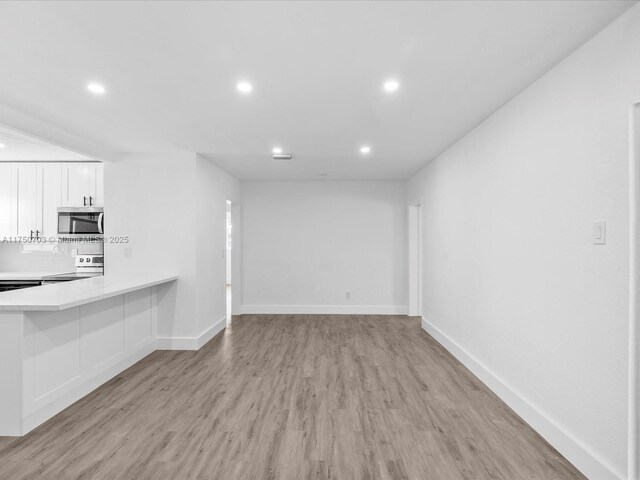 unfurnished living room featuring light wood-style flooring, baseboards, and recessed lighting