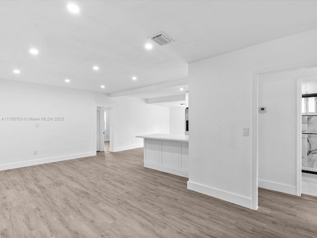 empty room with light wood-style floors, baseboards, visible vents, and recessed lighting