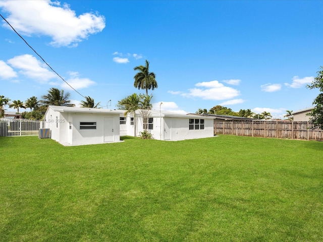 rear view of house featuring stucco siding, a fenced backyard, a lawn, and central air condition unit