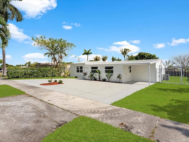 view of front of home with concrete driveway, a front yard, fence, a carport, and cooling unit