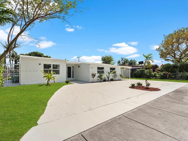 view of front of house featuring stucco siding, concrete driveway, and a front yard