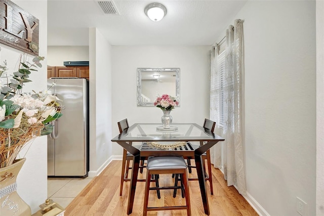 dining area featuring light wood-style flooring, visible vents, and baseboards