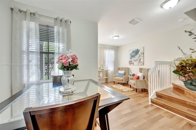 dining room with a wealth of natural light, stairway, wood finished floors, and visible vents