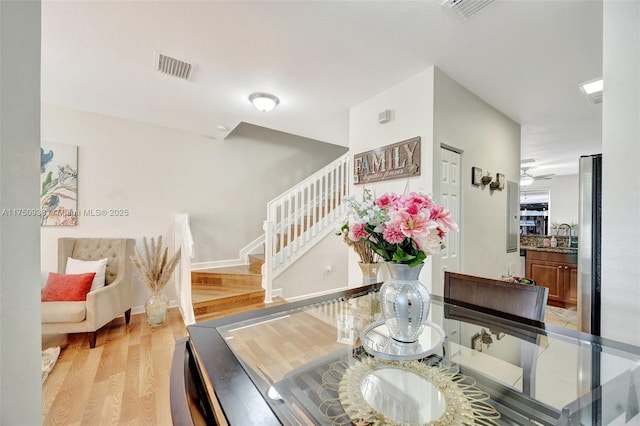 dining space with stairs, light wood-type flooring, visible vents, and baseboards