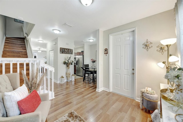 foyer entrance with light wood-style floors, baseboards, and stairs