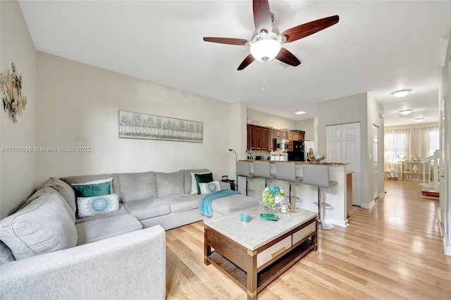 living room with ceiling fan, light wood-type flooring, and baseboards