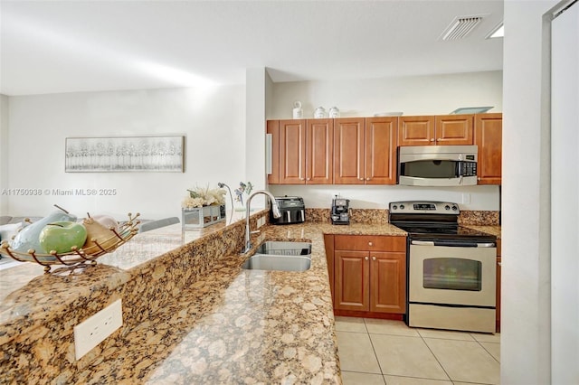 kitchen featuring light tile patterned floors, stainless steel appliances, visible vents, a sink, and light stone countertops