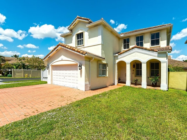 mediterranean / spanish home featuring stucco siding, a front lawn, a tile roof, decorative driveway, and a garage