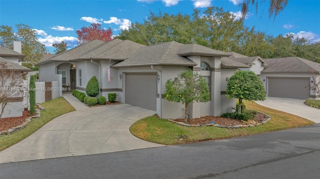 view of front of home featuring an attached garage, a shingled roof, concrete driveway, and stucco siding