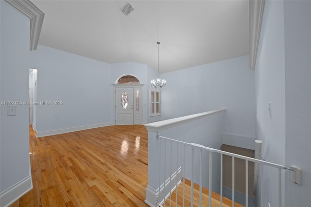 spare room with visible vents, vaulted ceiling, wood finished floors, a chandelier, and baseboards