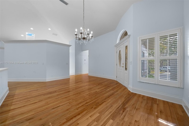 spare room featuring a notable chandelier, high vaulted ceiling, and light wood-style floors