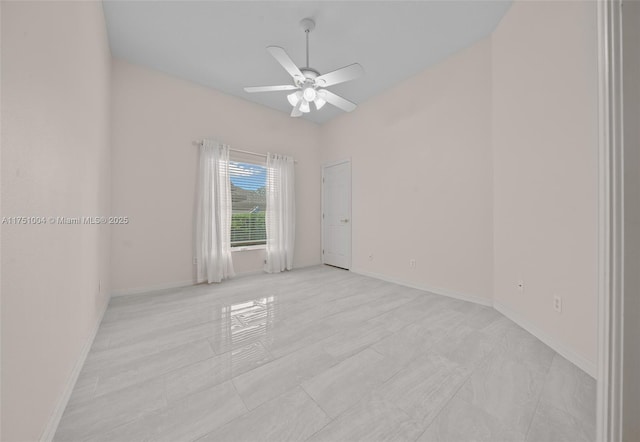 unfurnished room featuring a ceiling fan and baseboards