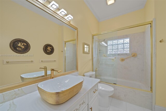 bathroom with toilet, vanity, ornamental molding, combined bath / shower with glass door, and tile patterned floors