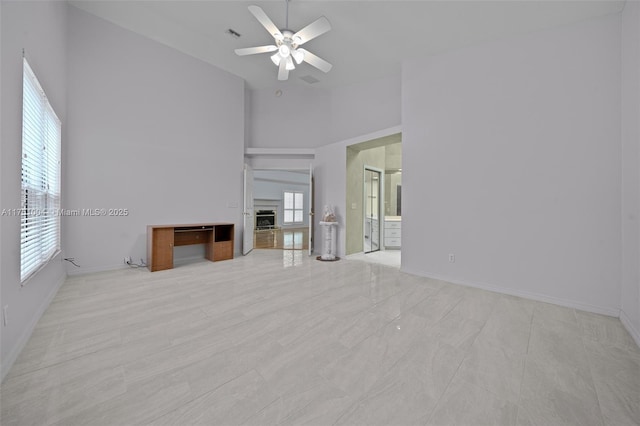 unfurnished living room with ceiling fan, high vaulted ceiling, a fireplace, and a healthy amount of sunlight