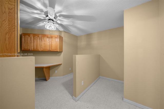 corridor featuring a textured ceiling, light carpet, and baseboards