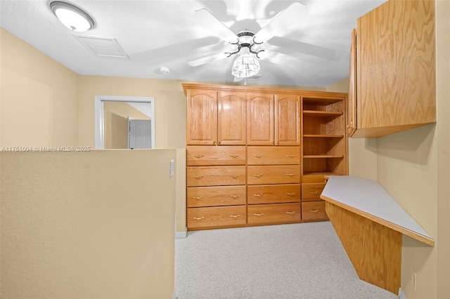 spacious closet with light carpet, ceiling fan, visible vents, and attic access