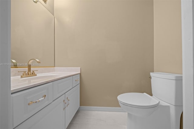 half bath with toilet, marble finish floor, vanity, and baseboards