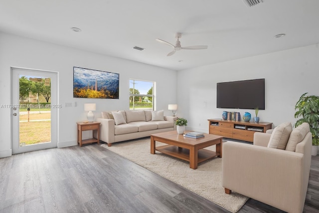 living room with light wood-style floors, ceiling fan, visible vents, and baseboards