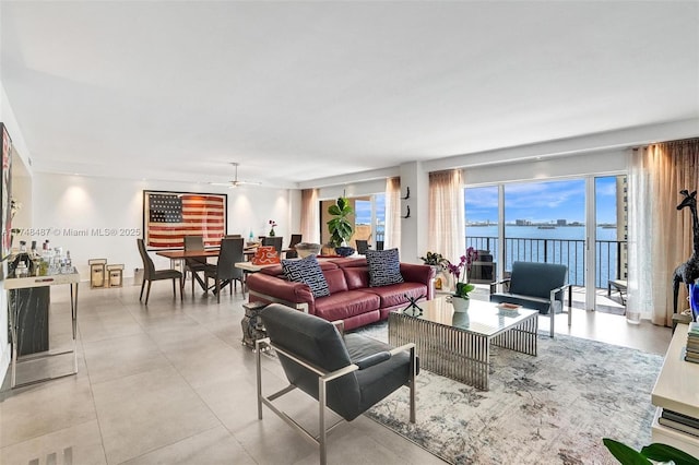 living area with a water view, ceiling fan, and light tile patterned floors