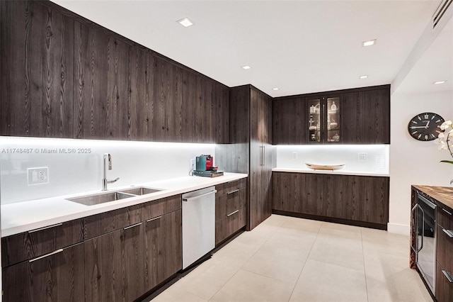 kitchen with a sink, glass insert cabinets, light countertops, and stainless steel dishwasher