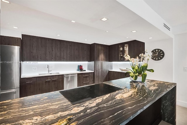 kitchen featuring modern cabinets, glass insert cabinets, stainless steel appliances, and a sink