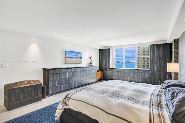 bedroom featuring a water view and light tile patterned floors