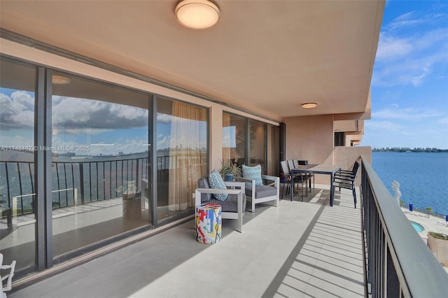 balcony with outdoor dining area and a water view