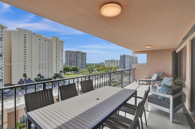 balcony with outdoor dining space and a city view