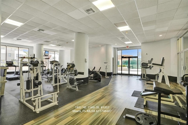 exercise room with a drop ceiling, visible vents, and baseboards