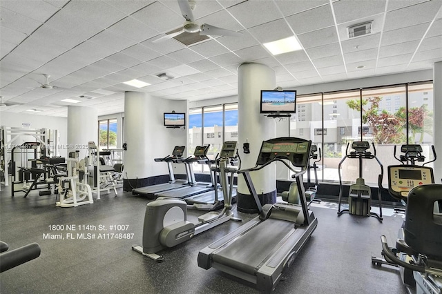 exercise room featuring visible vents, a paneled ceiling, and baseboards