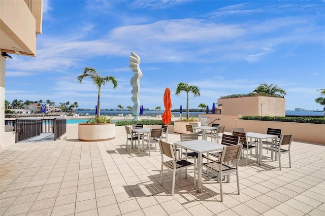 view of patio with outdoor dining space, a water view, and a community pool