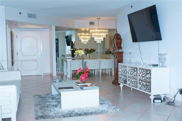 living area with a chandelier, visible vents, and light tile patterned floors