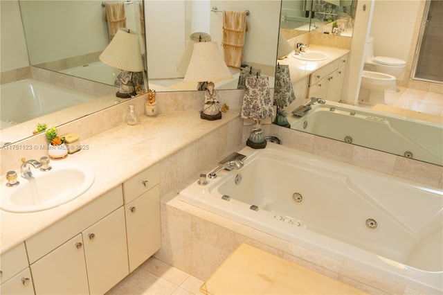 bathroom with tile patterned flooring, toilet, vanity, a whirlpool tub, and a bidet