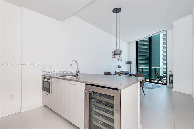 kitchen featuring wine cooler, decorative light fixtures, expansive windows, stainless steel oven, and a sink