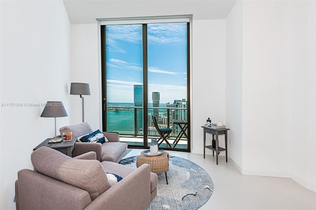 living area featuring expansive windows, plenty of natural light, a view of city, and baseboards