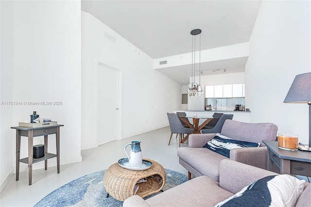 living room featuring concrete flooring, rail lighting, and visible vents