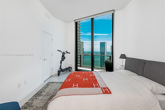 bedroom featuring expansive windows, a view of city, and access to exterior