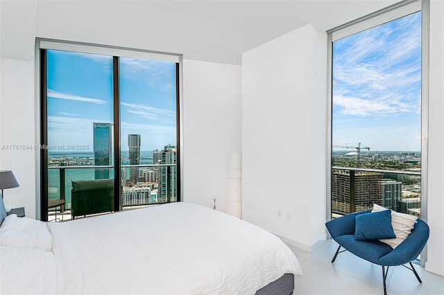 bedroom featuring a view of city, a wall of windows, and a water view