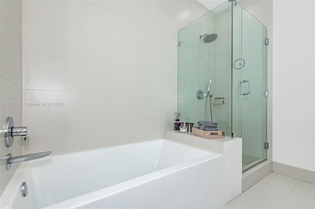 full bathroom featuring a stall shower, tile patterned flooring, and a garden tub