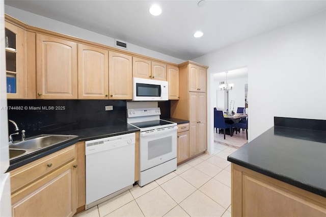 kitchen with dark countertops, white appliances, visible vents, and a sink