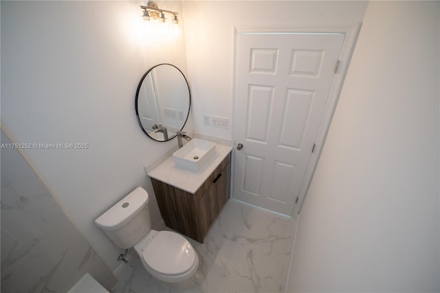 bathroom featuring toilet, marble finish floor, and vanity