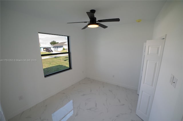 spare room featuring marble finish floor, baseboards, and a ceiling fan