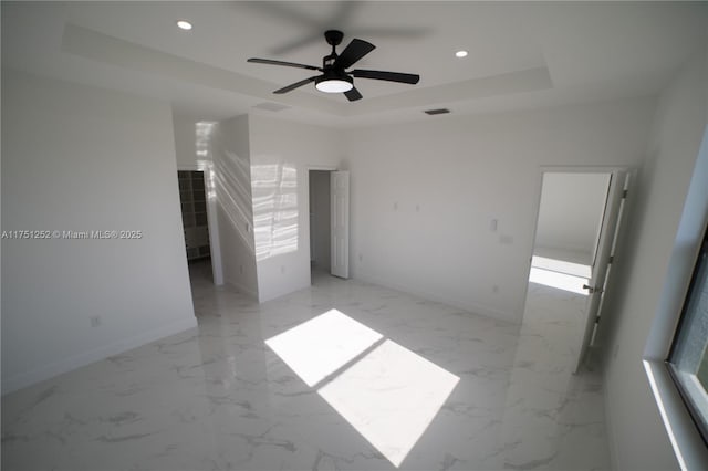 unfurnished bedroom with baseboards, visible vents, marble finish floor, a tray ceiling, and recessed lighting