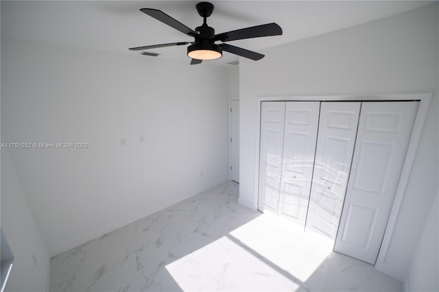 unfurnished bedroom featuring a closet, marble finish floor, ceiling fan, and baseboards