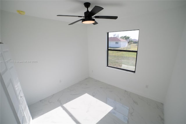 unfurnished room featuring marble finish floor and a ceiling fan