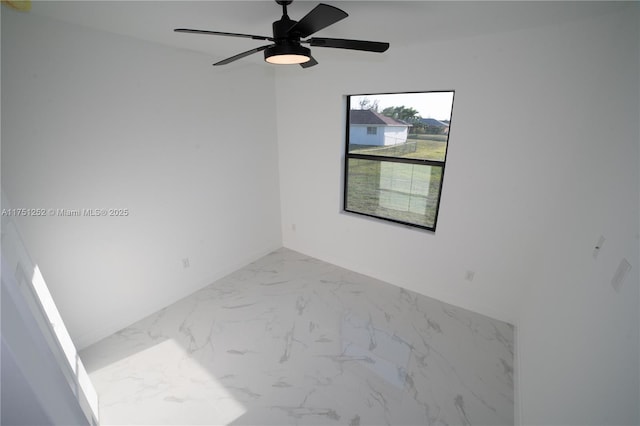 spare room featuring marble finish floor, a ceiling fan, and baseboards