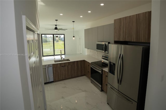 kitchen with appliances with stainless steel finishes, marble finish floor, light countertops, a sink, and recessed lighting