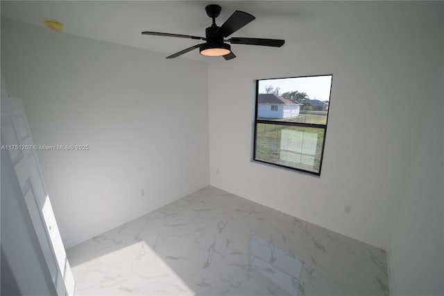 empty room featuring ceiling fan and marble finish floor